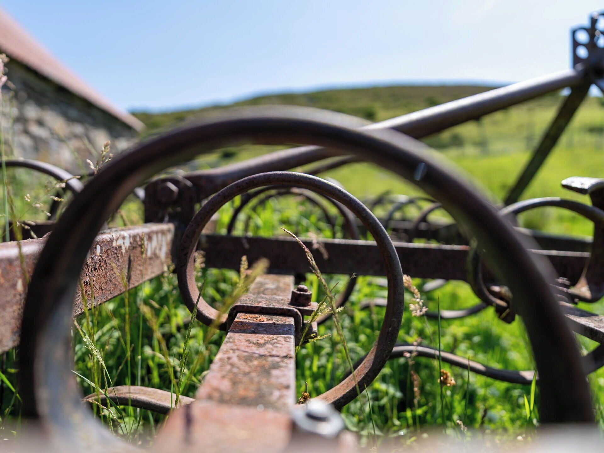 A bicycle wheel in a rural setting with a stone wall and green fields in the background.