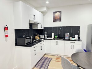 A modern kitchen with white cabinets, a black countertop, a microwave, a toaster, and a coffee maker.