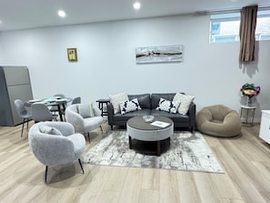 A modern living room with a grey sofa, armchairs, a coffee table, and a dining area with a table and chairs.