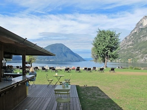 Une terrasse avec coin salon extérieur donnant sur un lac et des montagnes.