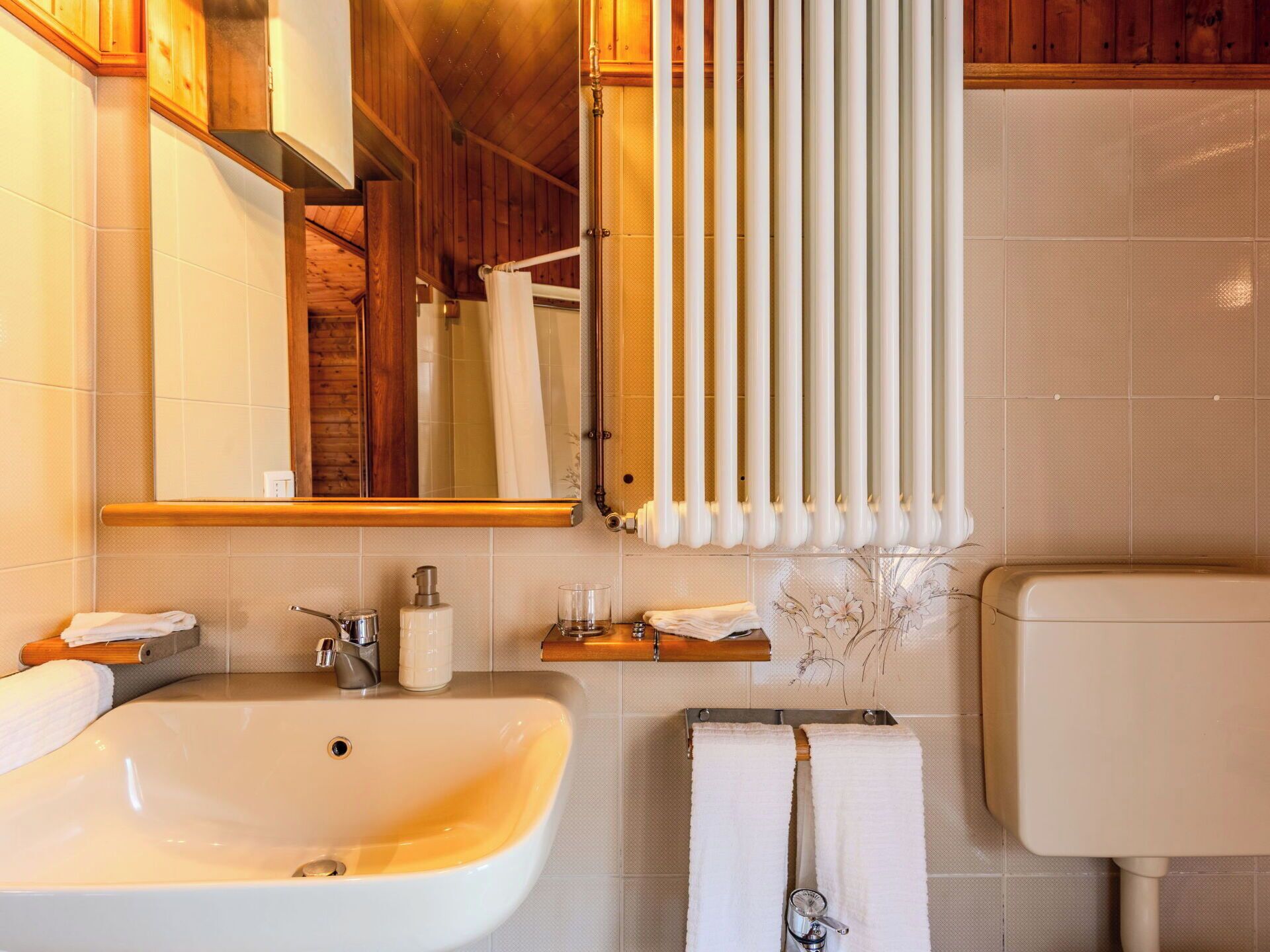 Un baño con lavamanos, espejo, toallero y retrete.