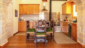 Una cocina con armarios de madera, un comedor con sillas y un arco de piedra.