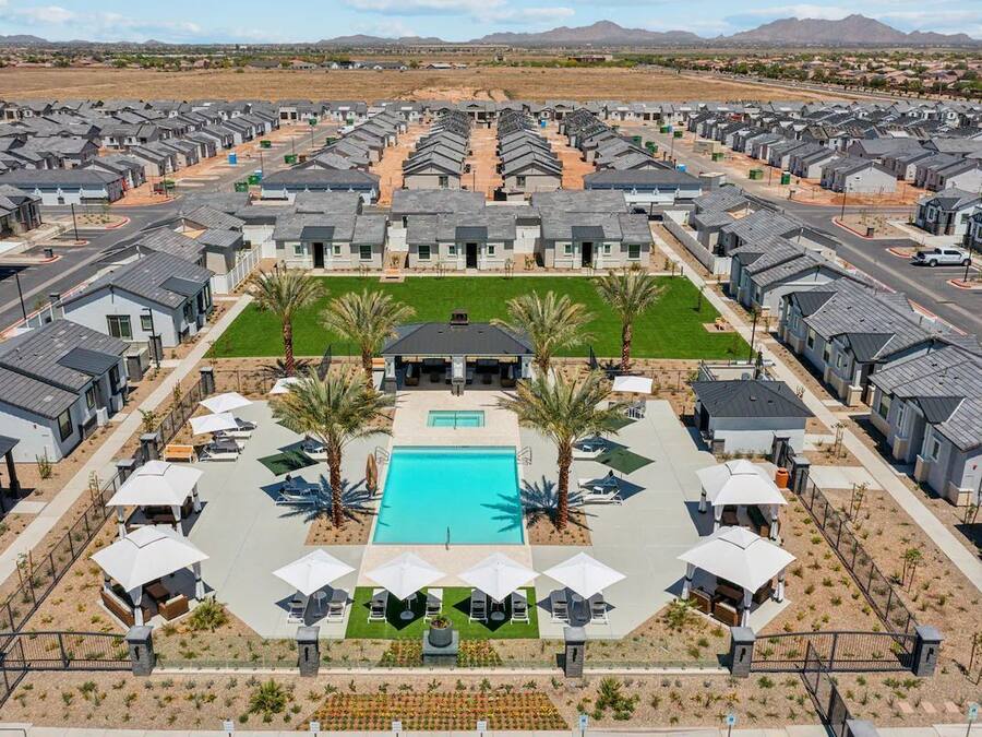 A residential complex with modern houses, a central swimming pool, and a landscaped area with palm trees.