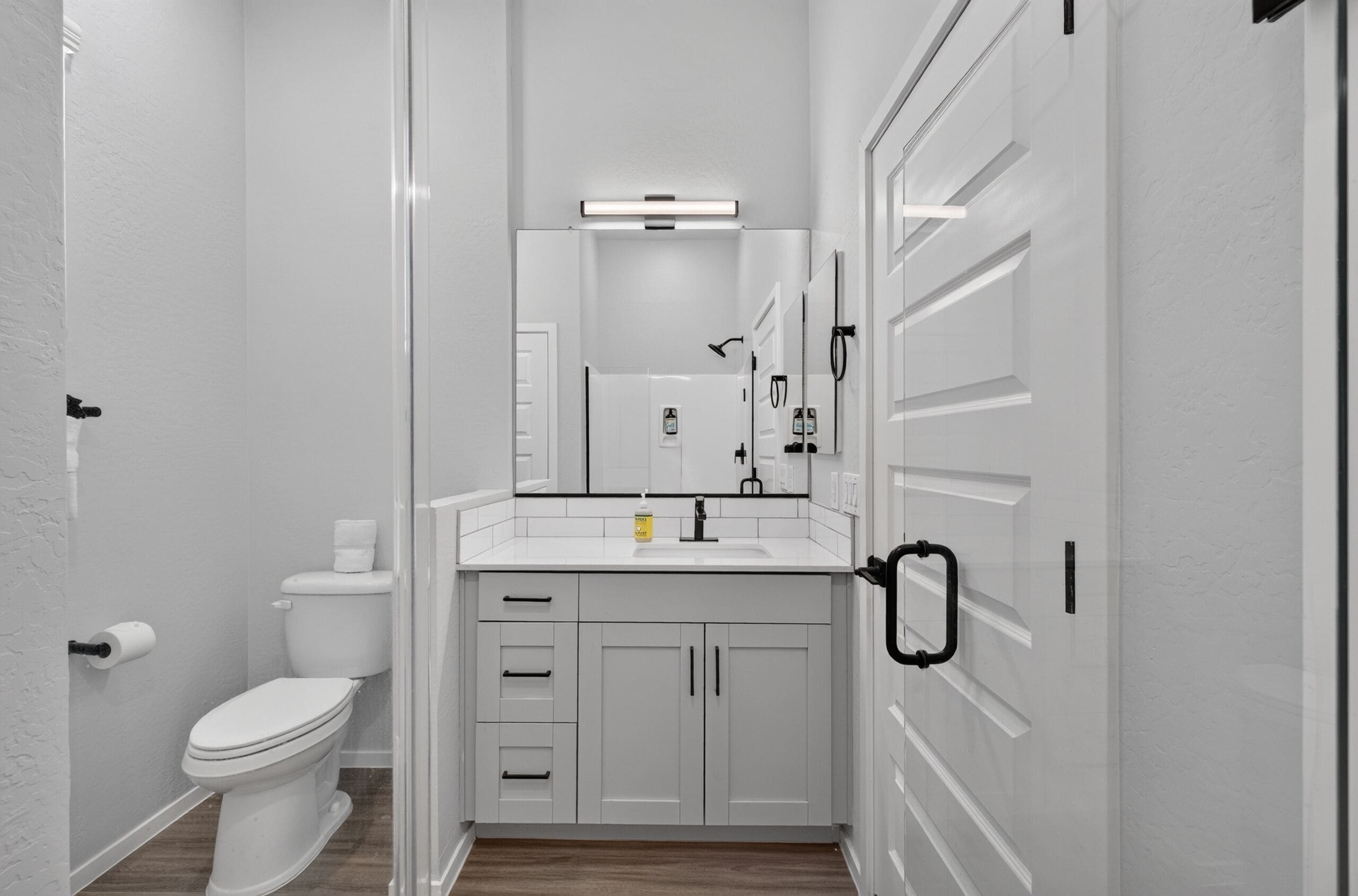 Ein Badezimmer mit Toilette, Waschbecken, Spiegel und Schränken.