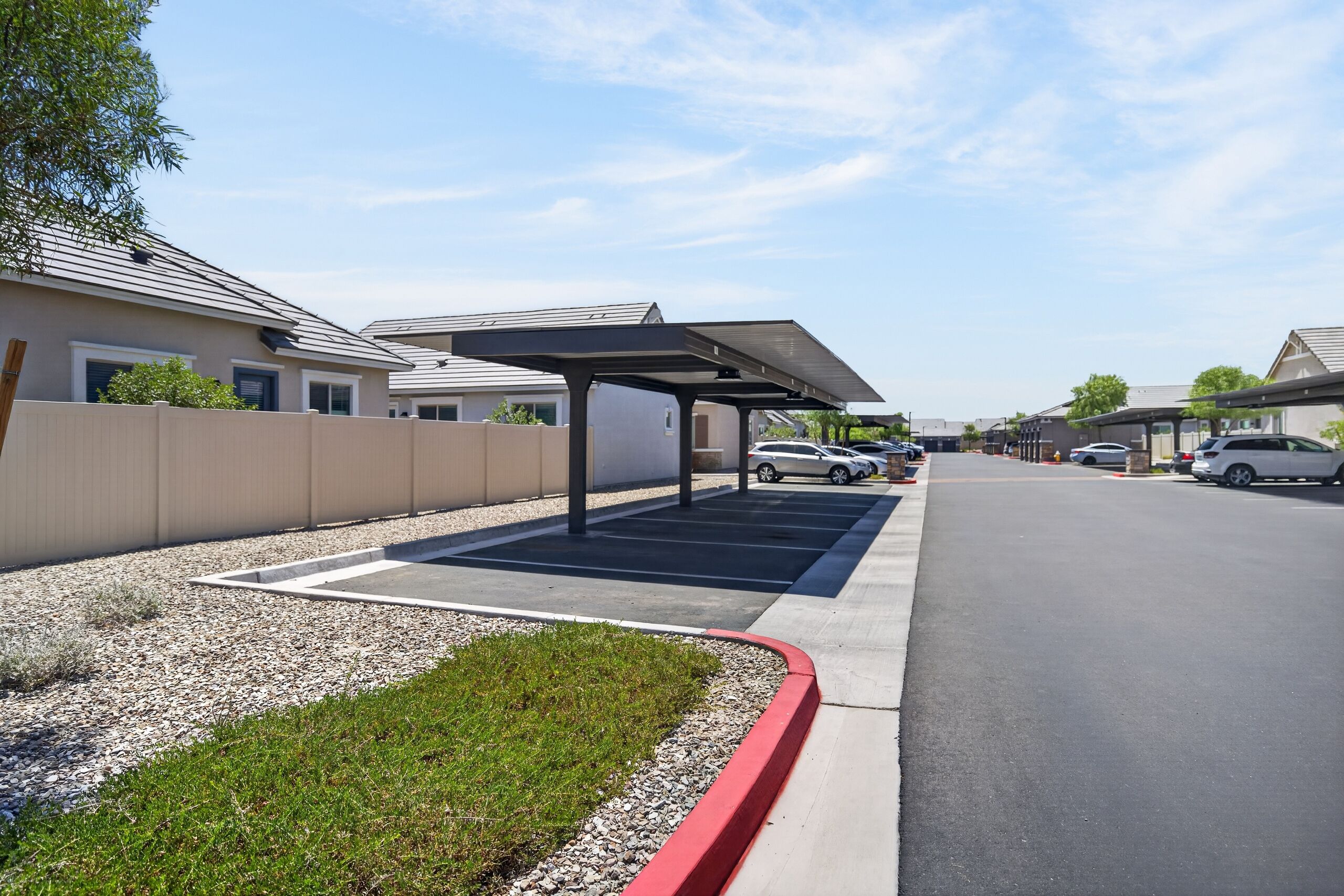A parking area with covered parking spaces and a clear sky.