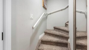 Una escalera con peldaños alfombrados y barandillas blancas.