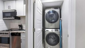 Cocina compacta equipada con microondas, estufa, lavavajillas y lavadora-secadora de doble puerta.