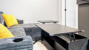 A modern living room with a grey sofa, yellow cushions, a black coffee table, and a white door in the background.