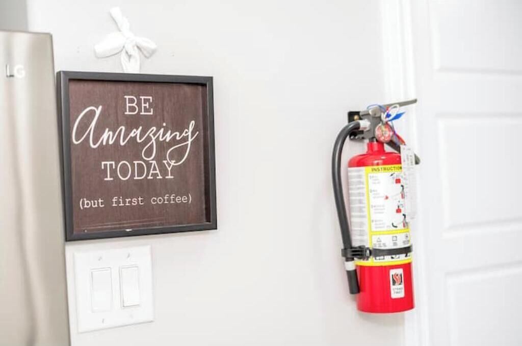 A framed motivational quote on a wall, a fire extinguisher mounted on the wall, and a white door.
