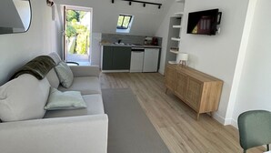 Een knus verblijf met een kitchenette, een bank, een eettafel en een televisie.