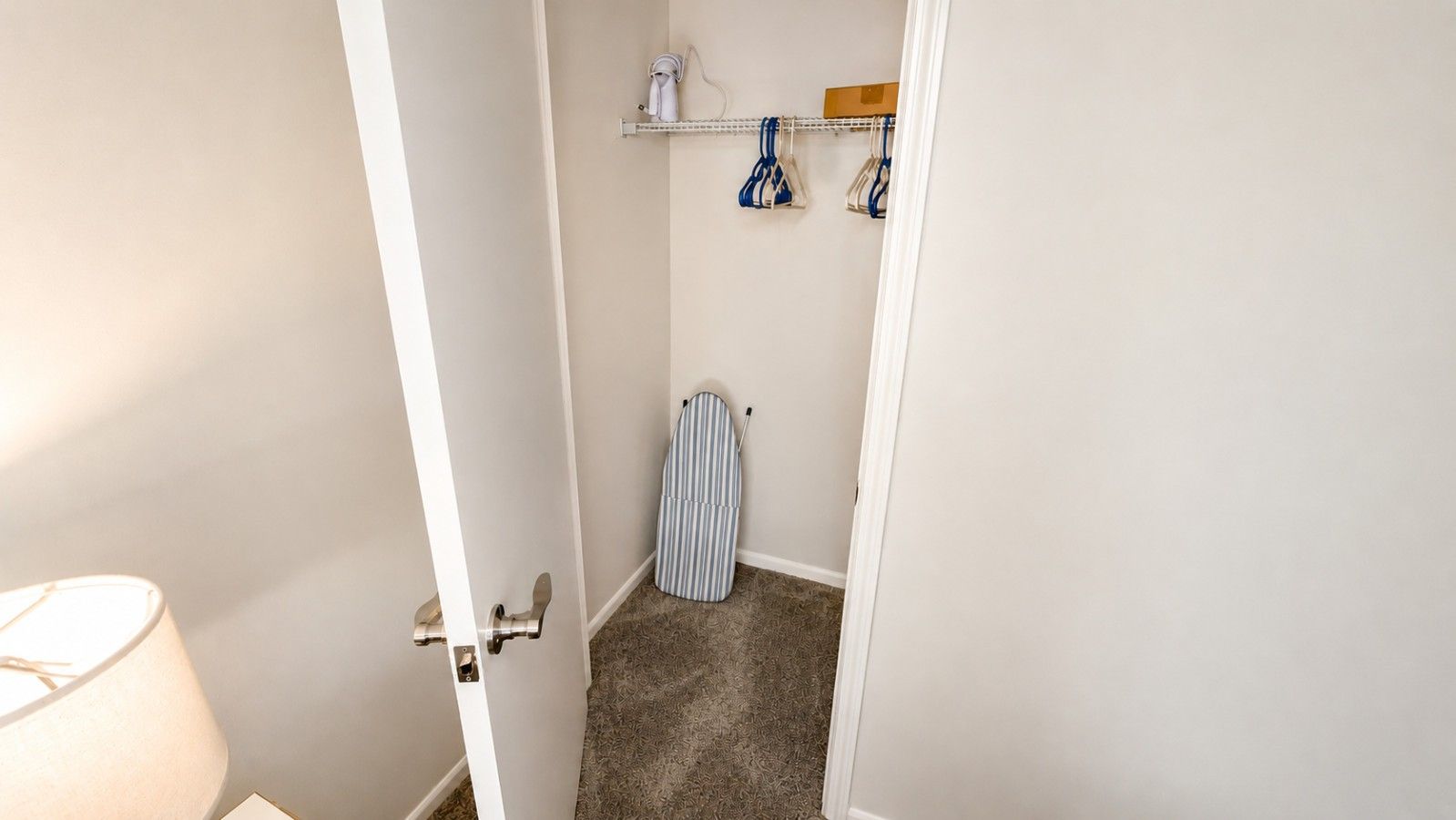 A narrow hallway with a door leading to a room.
