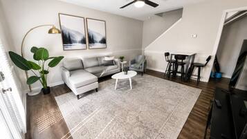 A living room with a sofa, coffee table, and a dining area with chairs.