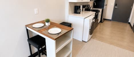 Una cocina compacta con comedor pequeño, lavadora y una puerta.