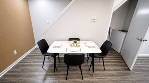 A dining area with a white table, black chairs, and a small plant centerpiece.