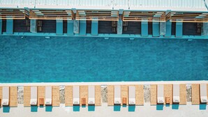A pool with wooden loungers and a stone wall. - Maessa Suites (Lukove)