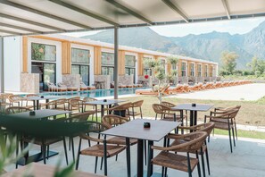 A poolside area with outdoor seating and a view of mountains. - Maessa Suites (Lukove)