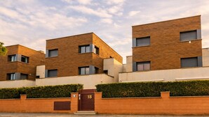 A modern residential building with a brick facade, multiple windows, and a gated entrance. - Duplex apartment 800 meters from the beach, in a high-end residential complex, in a quiet area (Castell d'Aro)
