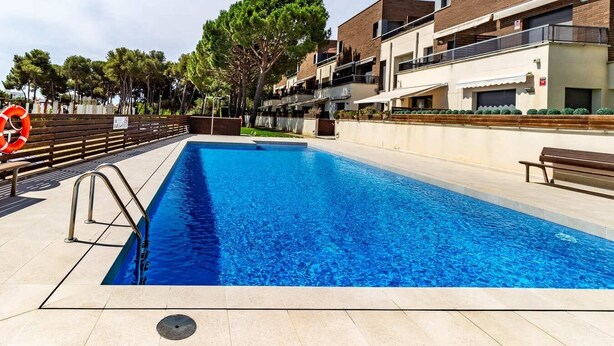 A rectangular swimming pool with a lifebuoy, surrounded by a tiled deck, and adjacent to a multi-story building with balconies. - Duplex apartment 800 meters from the beach, in a high-end residential complex, in a quiet area (Castell d'Aro)