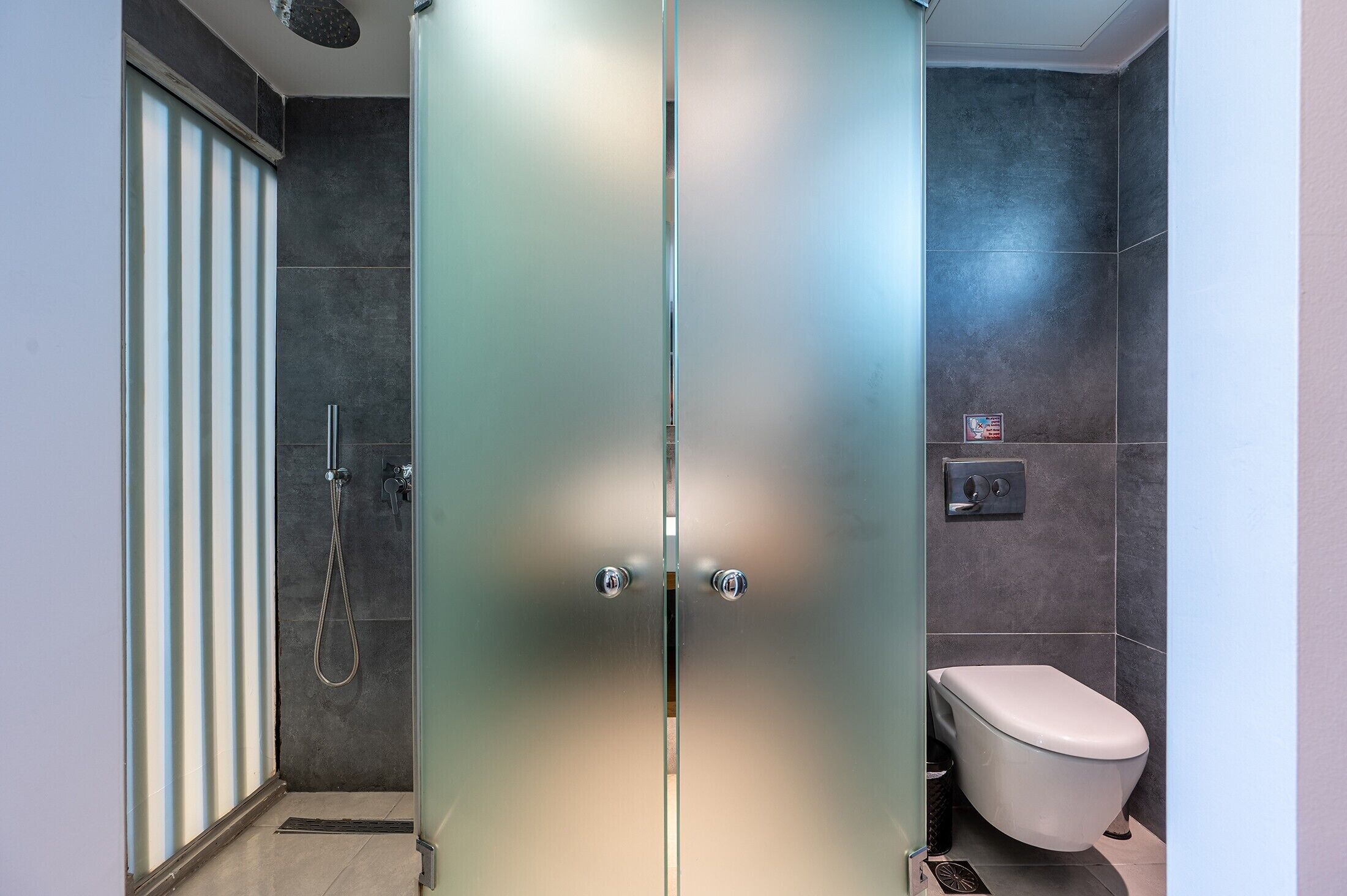 Un baño con ducha, inodoro y puertas de vidrio esmerilado.
