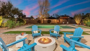 Un jardin avec une piscine, un foyer extérieur et des fauteuils Adirondack.