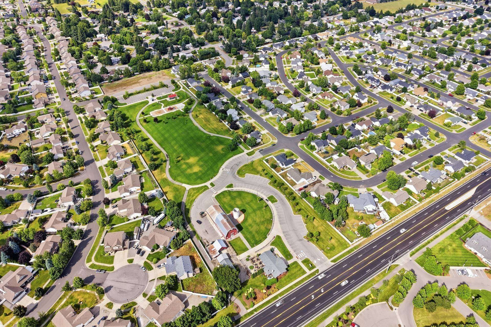 An aerial view of a residential area with houses, roads, and green spaces.