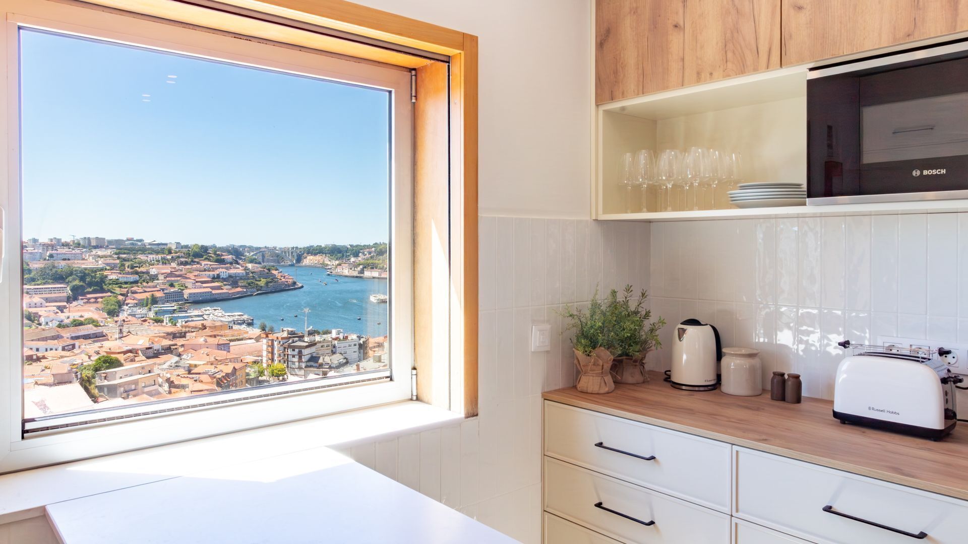 A modern kitchen with a view of a cityscape through a large window.