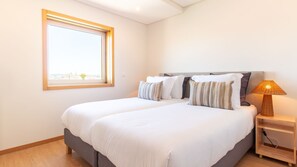 Une chambre à coucher avec un grand lit, une table de chevet avec une lampe et une fenêtre donnant sur un beau paysage.