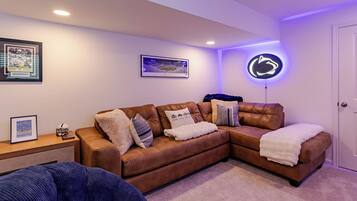 A cozy living room with a brown leather couch, a blue chair, and a framed picture on the side table.
