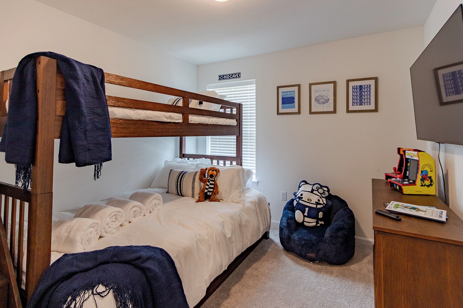 A bedroom with a bunk bed, a desk with a Hello Kitty plush toy, and a small arcade machine.