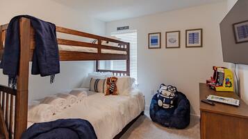 A bedroom with a bunk bed, a desk with a Hello Kitty plush toy, and a small arcade machine.