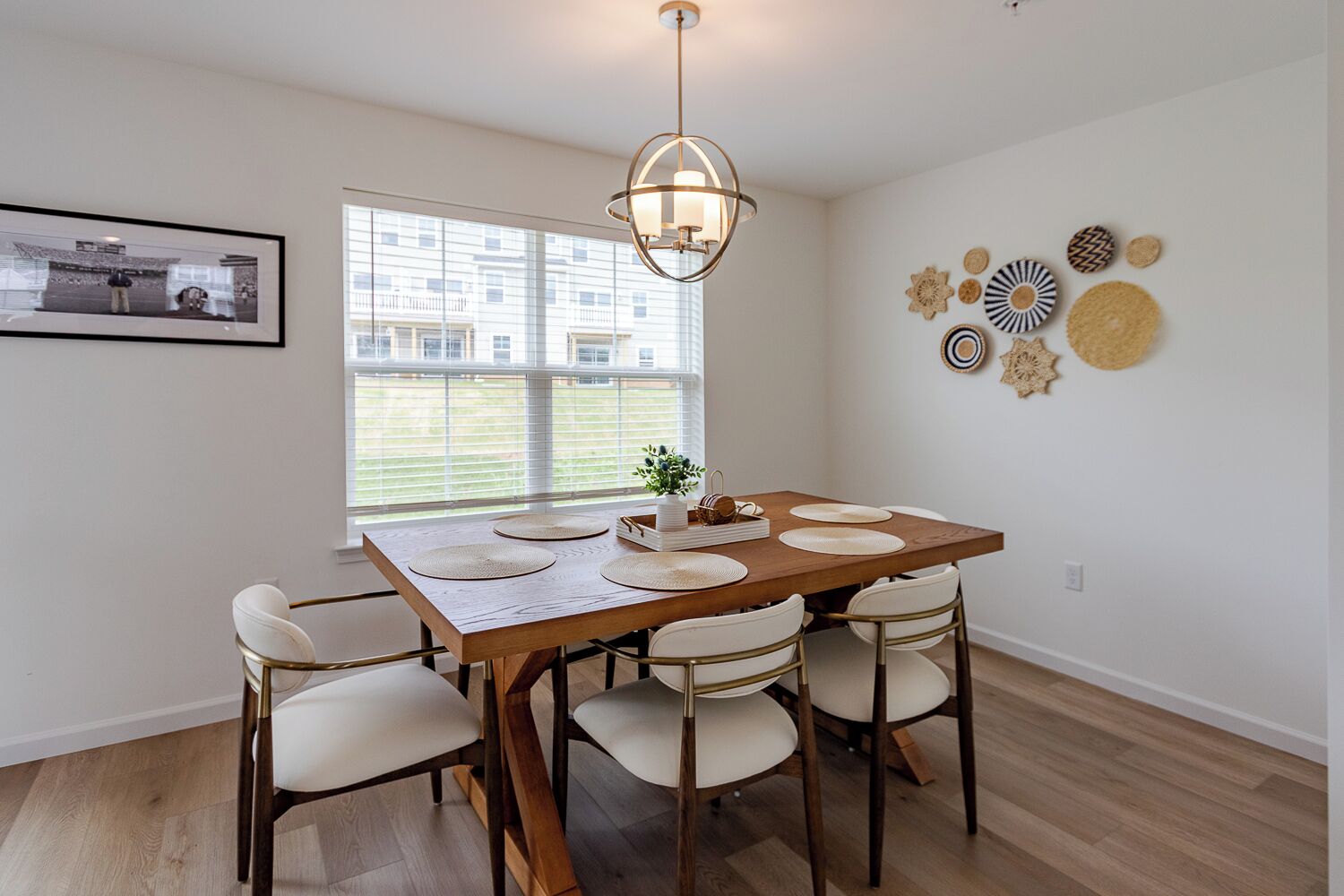 A dining area with a wooden table, white chairs, and a pendant light.