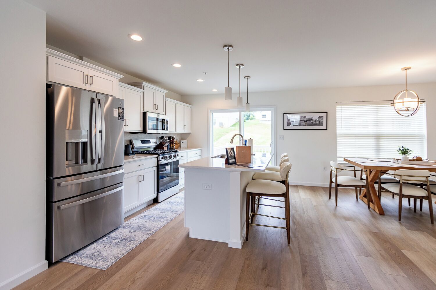 A modern kitchen with stainless steel appliances, a central island, and a dining area with a wooden table and chairs.
