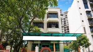 Un edificio con entrada protegida por una reja, un cartel que indica 'Collection' y 'GYO-Served', y un estilo arquitectónico moderno.