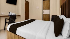 Una habitación de hotel con cama, escritorio, silla, televisor y armario.
