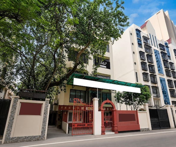 Un edificio con entrada porticada, un pasillo cubierto y un moderno rascacielos al fondo.