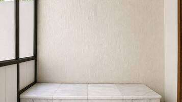 A corner of a room with a marble bench and a textured wall.