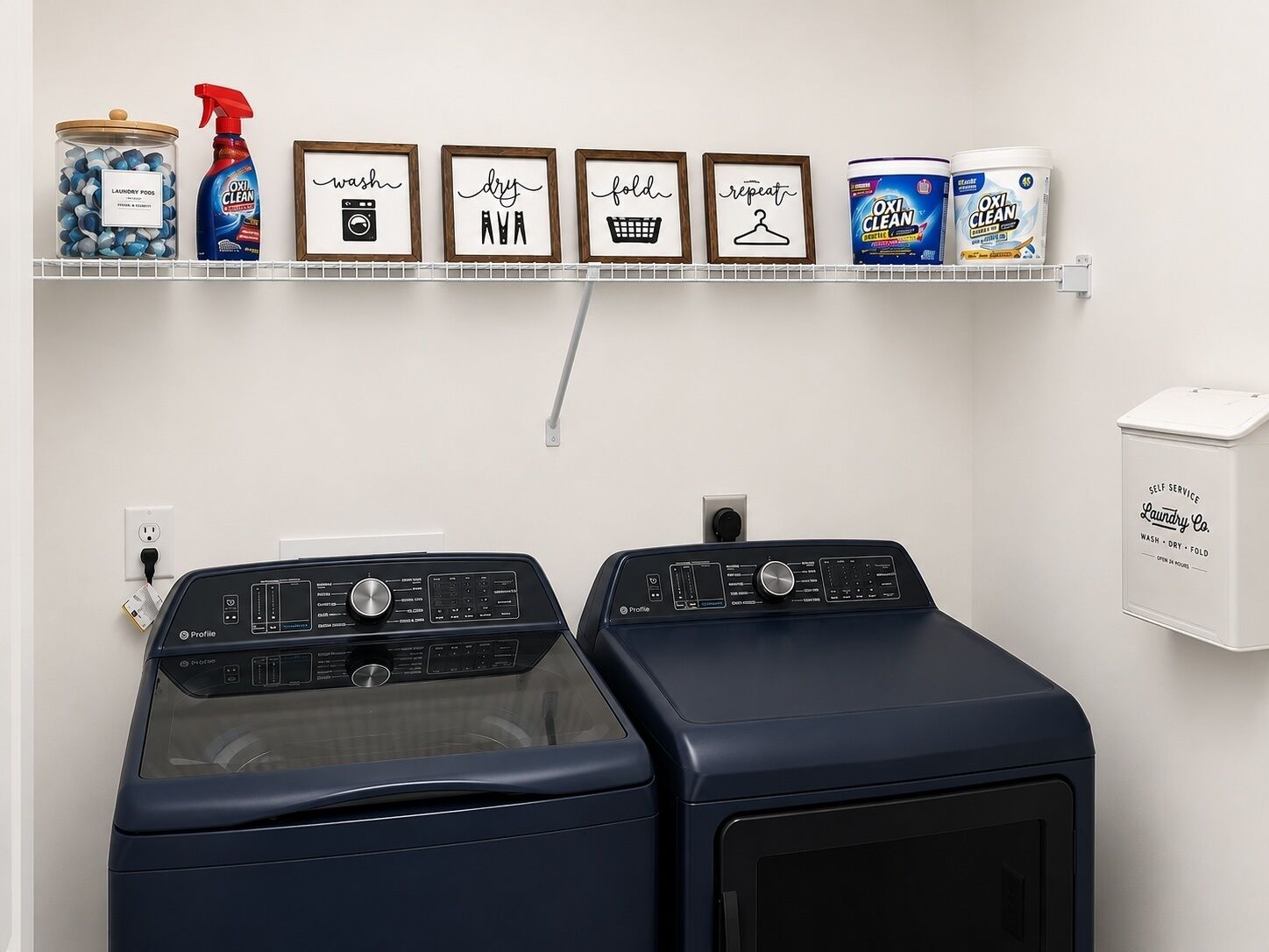 A laundry area with two front-loading washing machines, a shelf with laundry products, and a self-service laundry box.