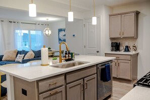 Una cocina moderna con una isla central, un fregadero y una estación de café.