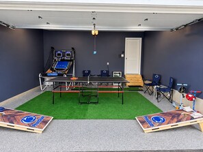 Una habitación con mesa de ping pong, sillas y una mesa de ping pong con un logo.