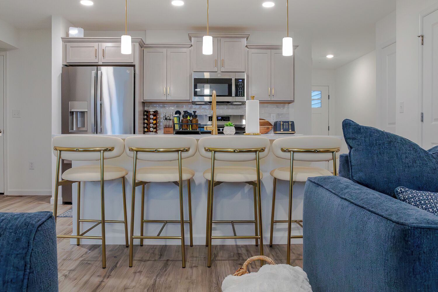 A modern kitchen with stainless steel appliances, a bar area with stools, and a seating area with sofas.