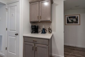 A kitchenette with a coffee maker, a kettle, and a coffee pot on the counter.