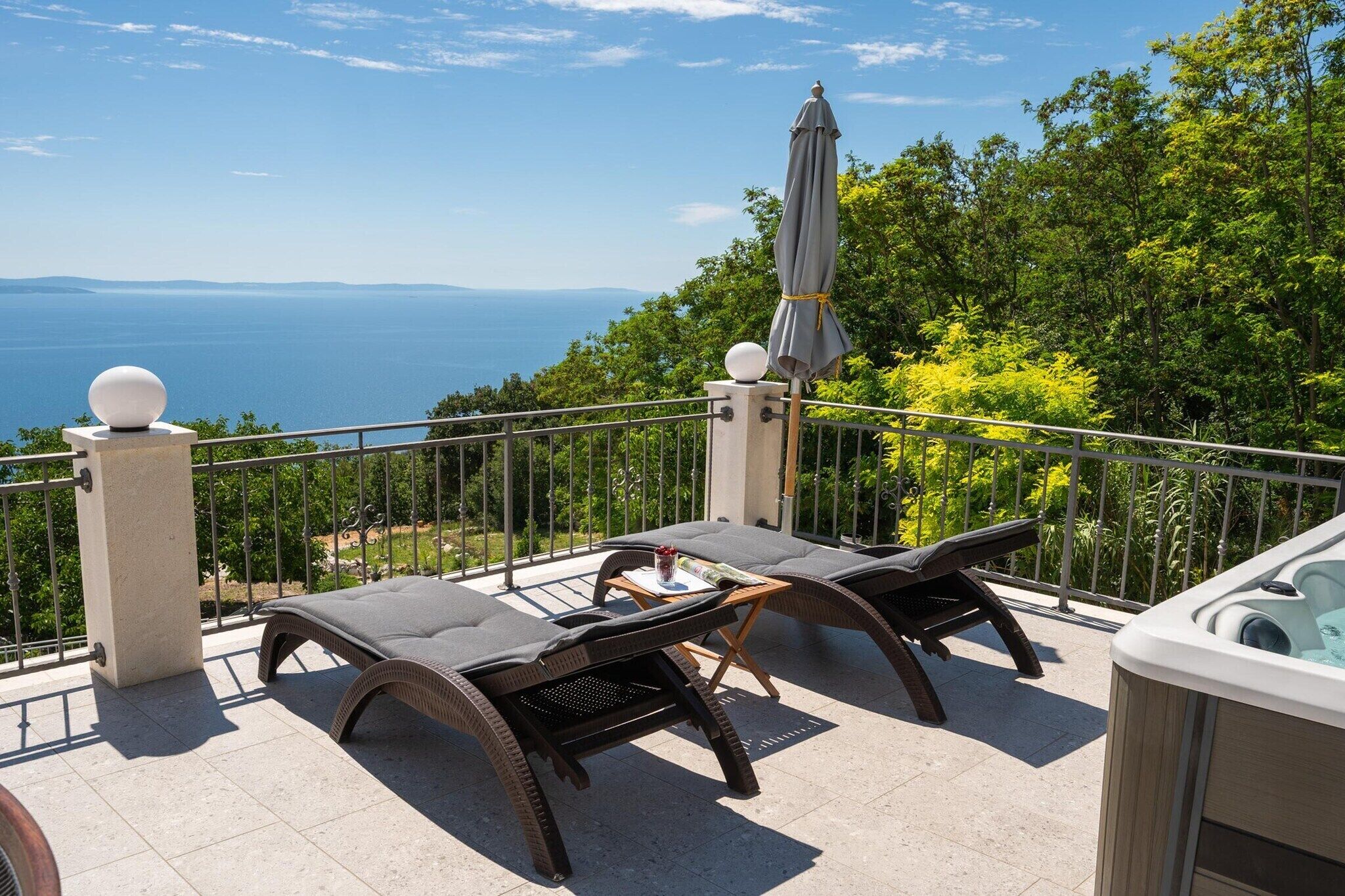 Ein Balkon mit zwei Liegestühlen, einem Tisch und einer Whirlwanne.
