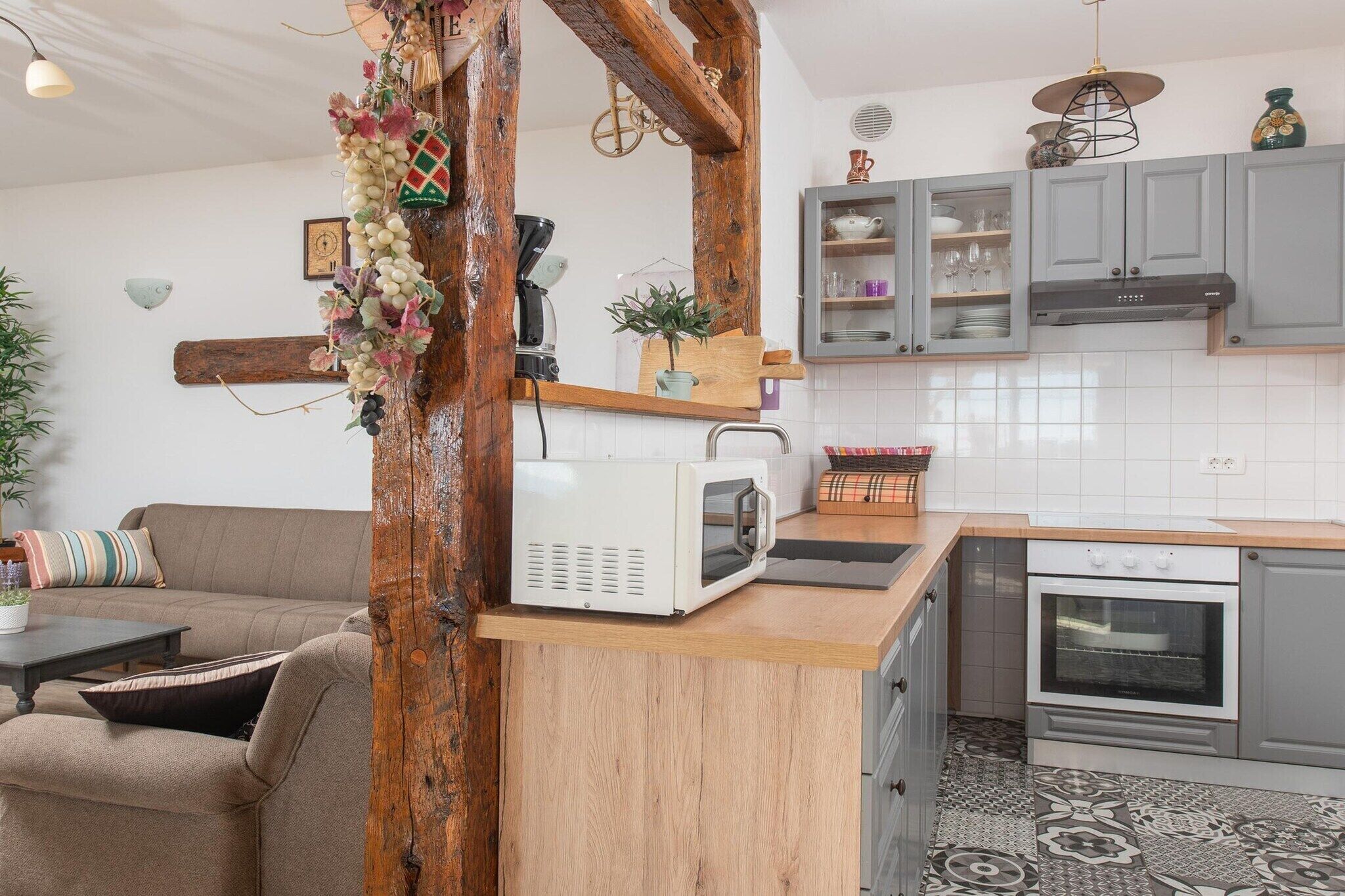 A kitchen with a microwave, oven, and grey cabinets.