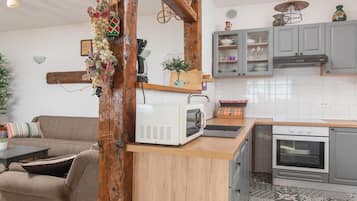 A kitchen with a microwave, oven, and grey cabinets.