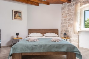 Ein Schlafzimmer mit Steinwand, einem hölzernen Bett und einem Fenster mit Blick.