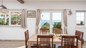 A dining area with a table, chairs, and a view of the sea. - Sea View Villa in Jesenice with Jacuzzi (Jesenice)