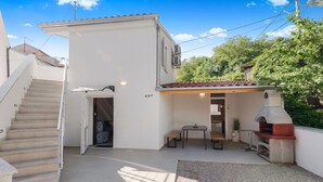 Una propiedad residencial con escaleras, un patio con mesa y sillas, y una zona de barbacoa.