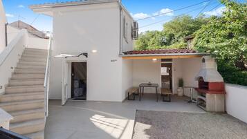 Una propiedad residencial con escaleras, un patio con mesa y sillas, y una zona de barbacoa.
