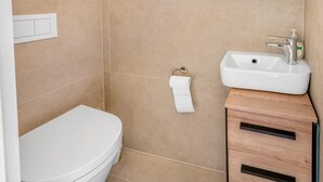 Un baño con inodoro, lavamanos y toallero.