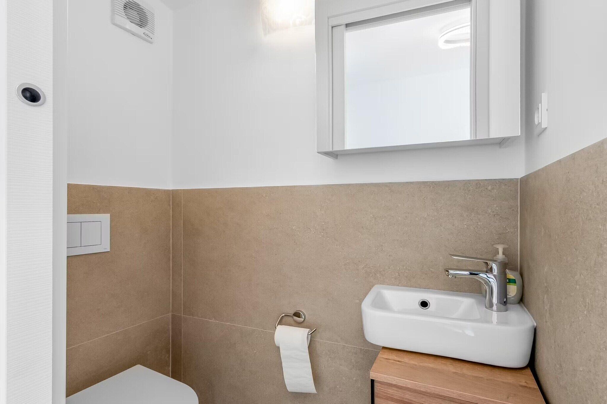 A bathroom with a white sink, a mirror, and a toilet.